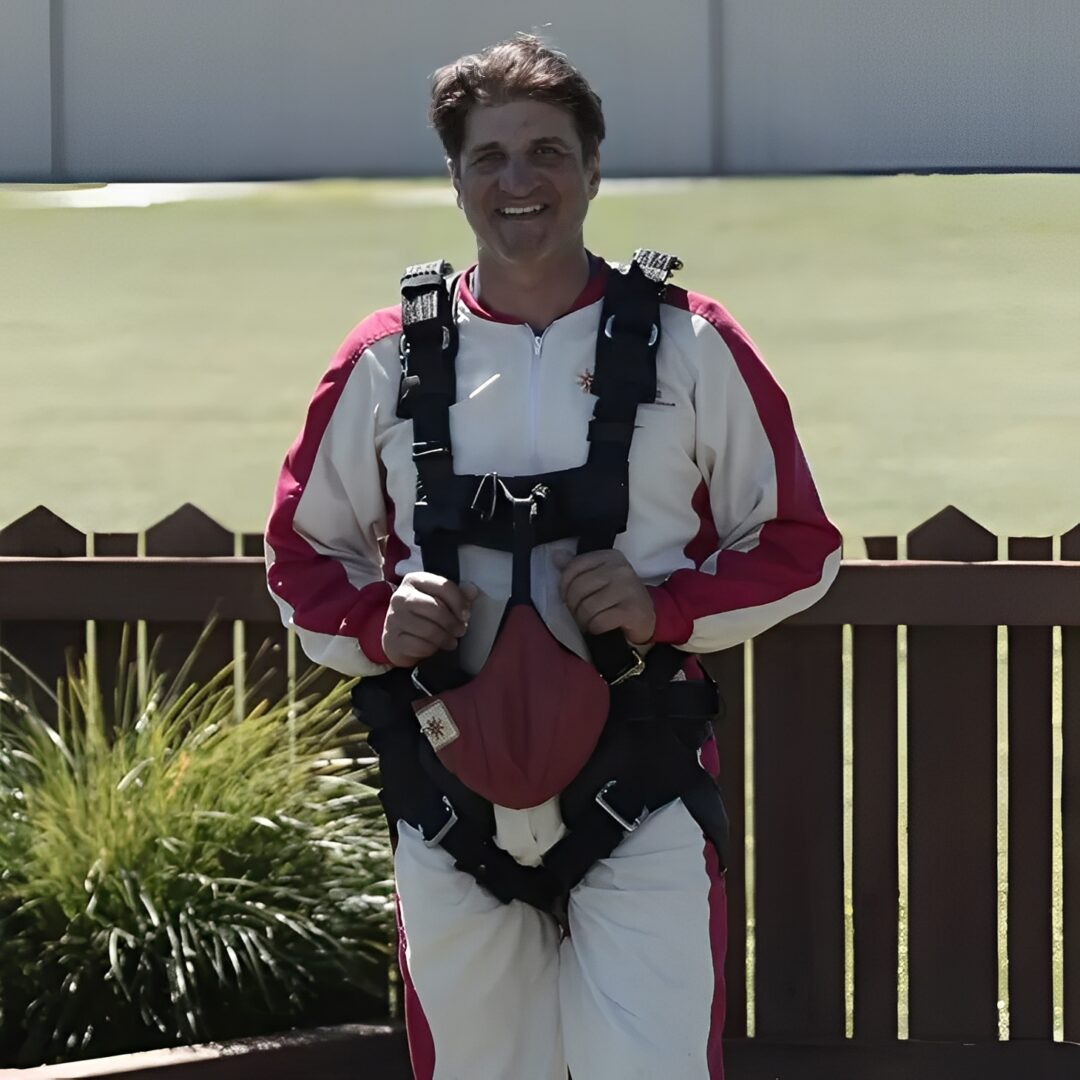 Person wearing skydiving outfit near wooden fence